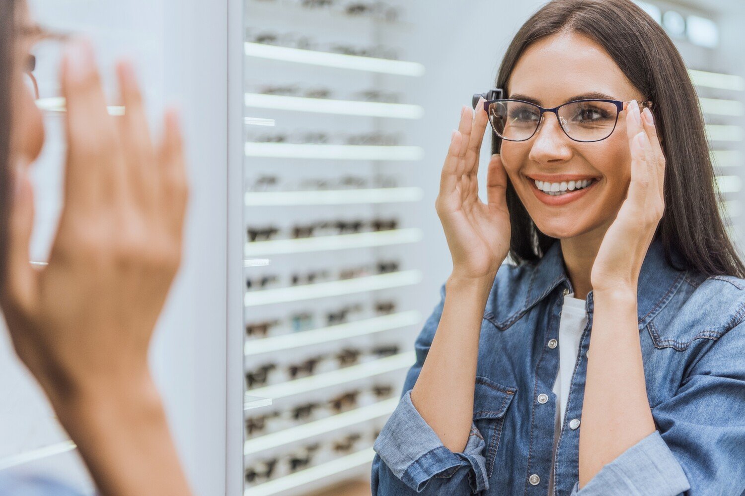 AdobeStock_225306377 v2 Woman tries on different eyeglass frames at Drake Eye Center located in Decatur and Hartselle AL